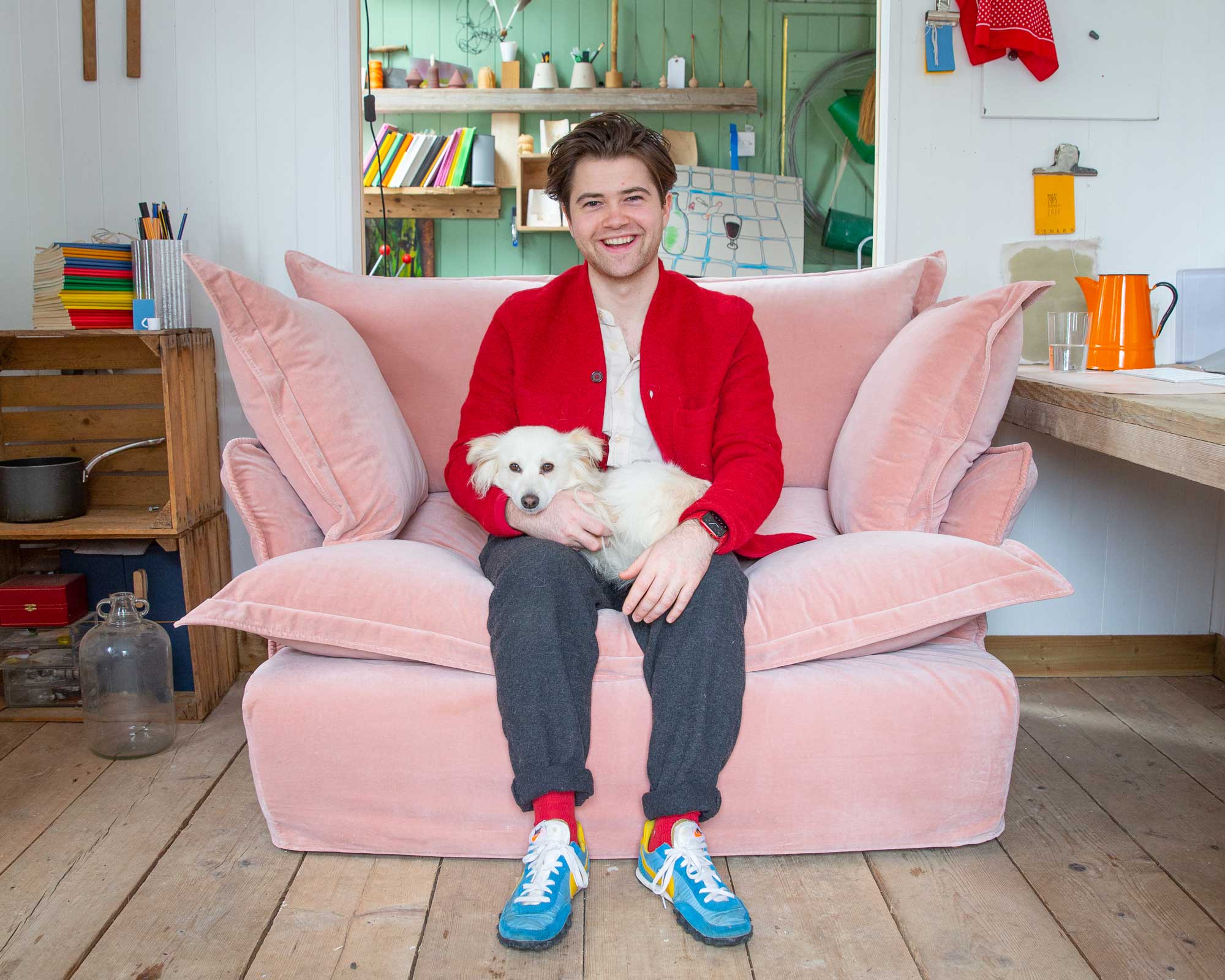Felix Conran and Apollo the dog on a MakerSon plaster pink velvet loveseat in Song pillow edge in his studio