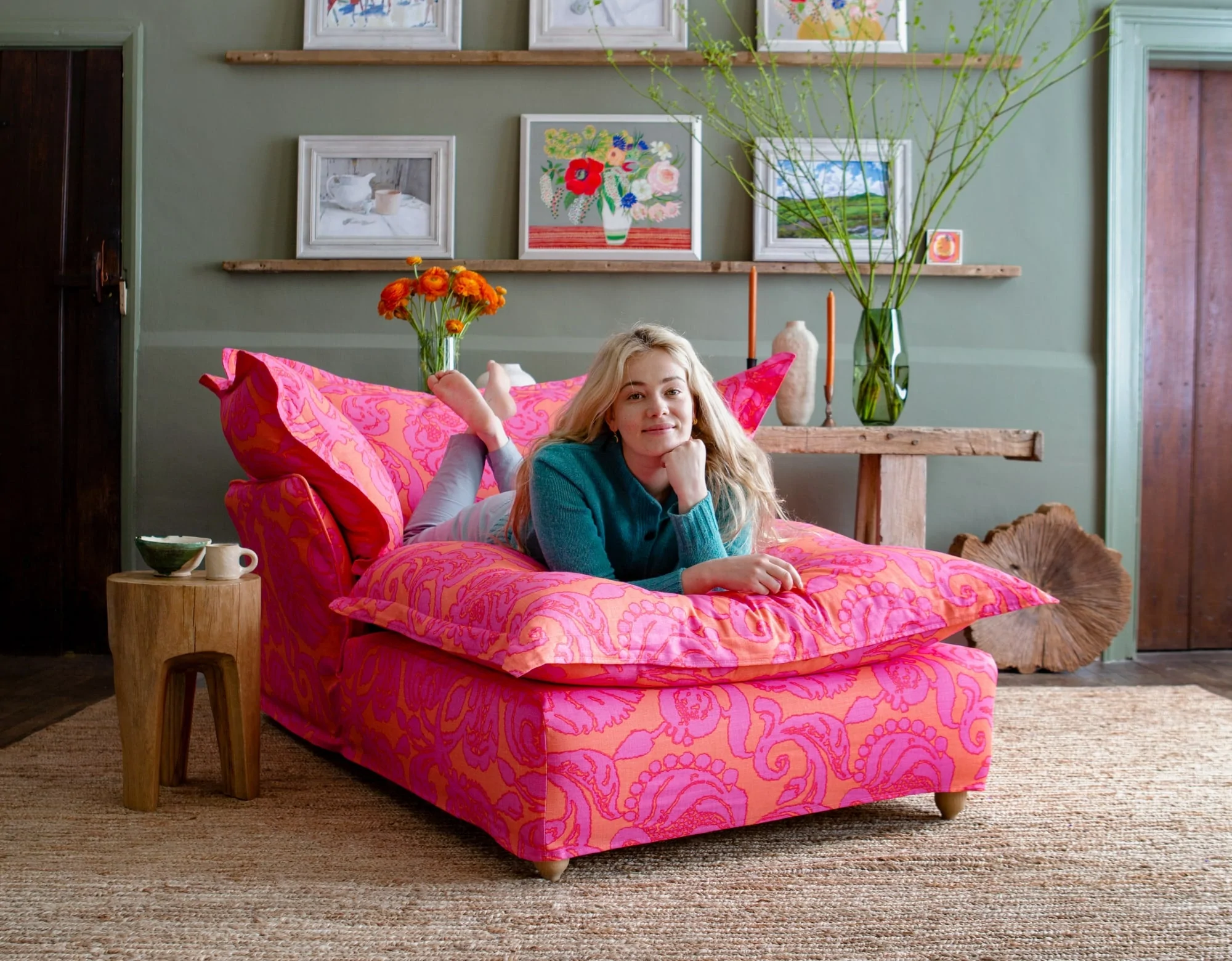 Marnie laying on a Maker and Son Song pillow edge Armchair Chaise in Christopher Farr bespoke pink and orange Anna print